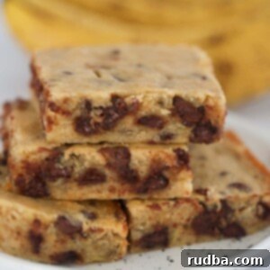 Decadent Chocolate Banana Squares 2 chocolate banana bars on a plate with ripe bananas in the background.
