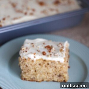 Southern Sweet Hummingbird Sheet Cake 2 A slice of hummingbird sheet cake on a blue plate, garnished with pecans.