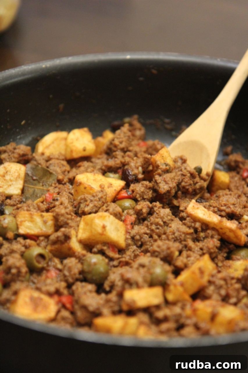 A close-up of Cuban Picadillo showing ground beef, olives, and capers in a rich, savory sauce.