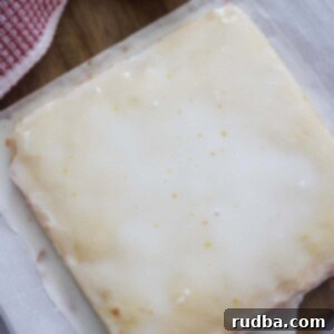 Tangy White Chocolate Lemon Blondies 2 white chocolate lemon blondies on a cutting board with a lemon on the side.