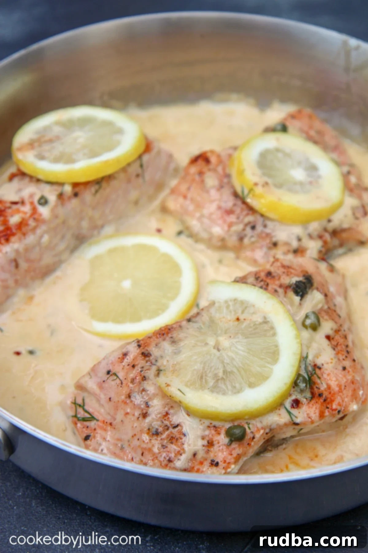 salmon with a creamy lemon sauce in a stainless steel skillet