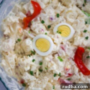 Creamy Puerto Rican potato salad garnished with slices of hard-boiled egg and vibrant pimientos.