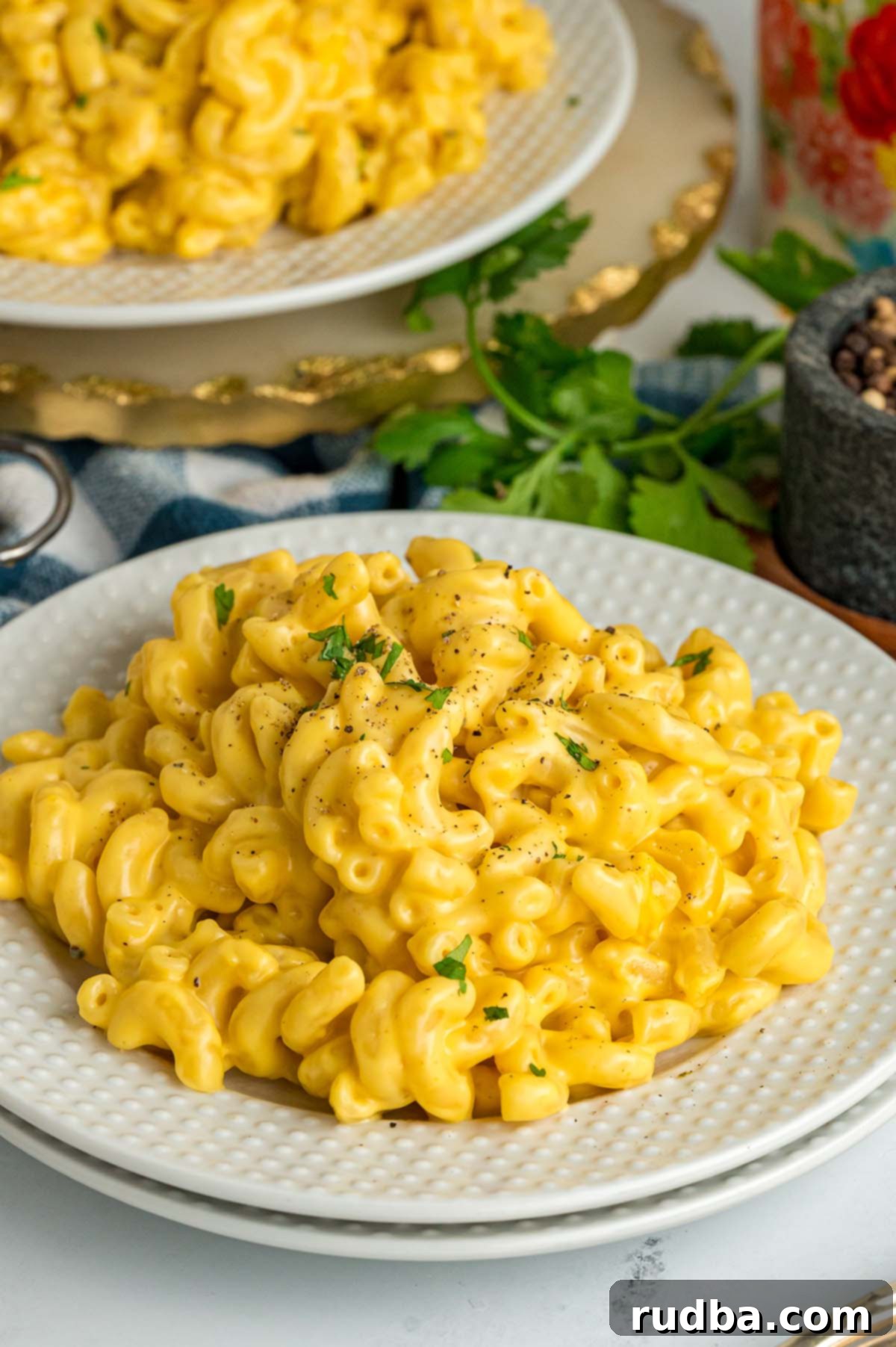 A serving of creamy homemade mac and cheese on a white plate, garnished with a sprig of fresh parsley.