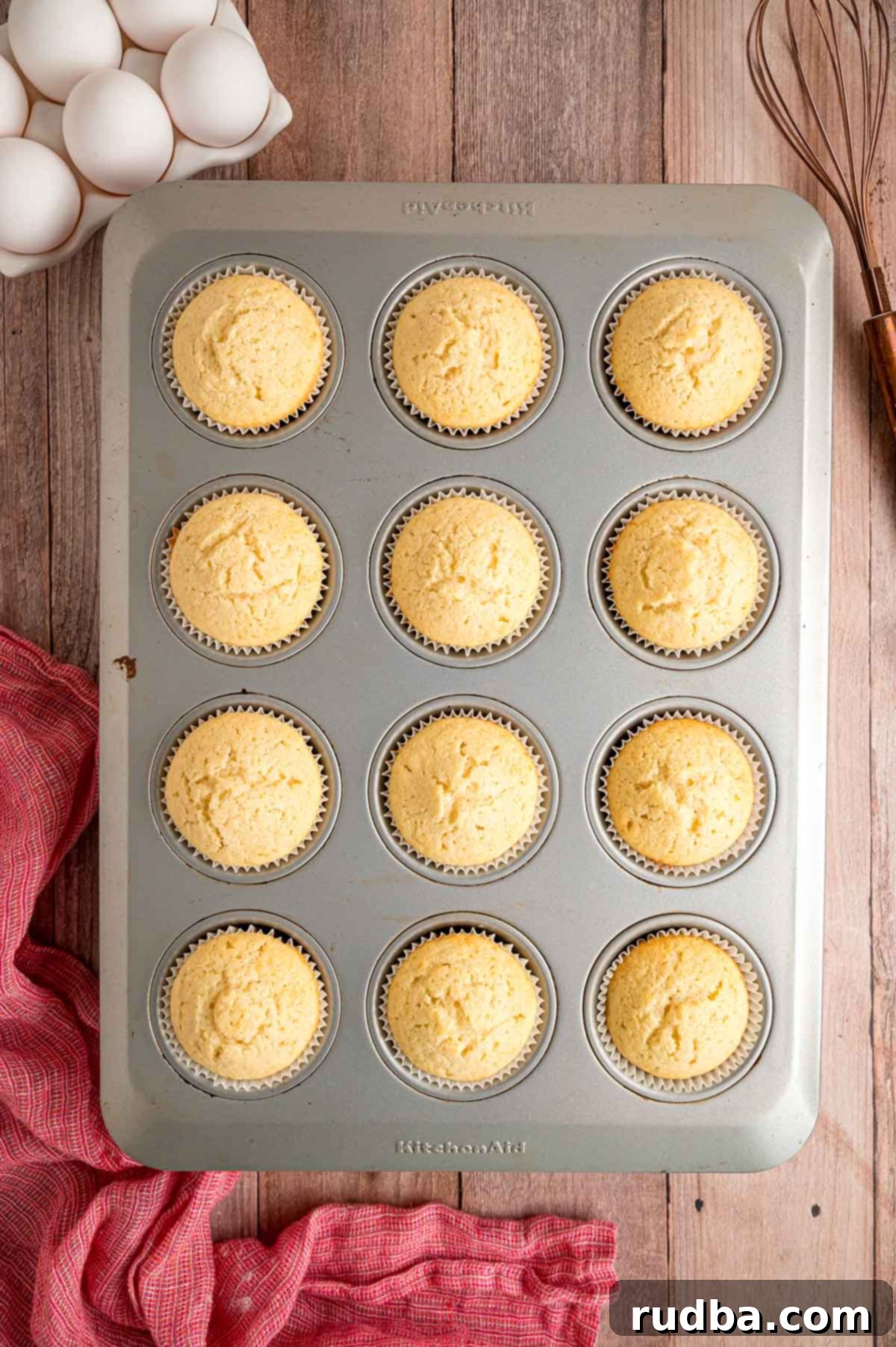 Velvety Vanilla Cupcakes 4 Freshly baked vanilla cupcakes nestled in a baking tin, cooling down before they are frosted.