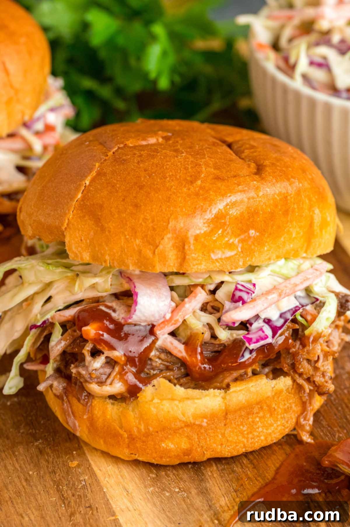 Pulled pork sandwich with coleslaw on top, showcasing the layers of juicy pork and crisp coleslaw.
