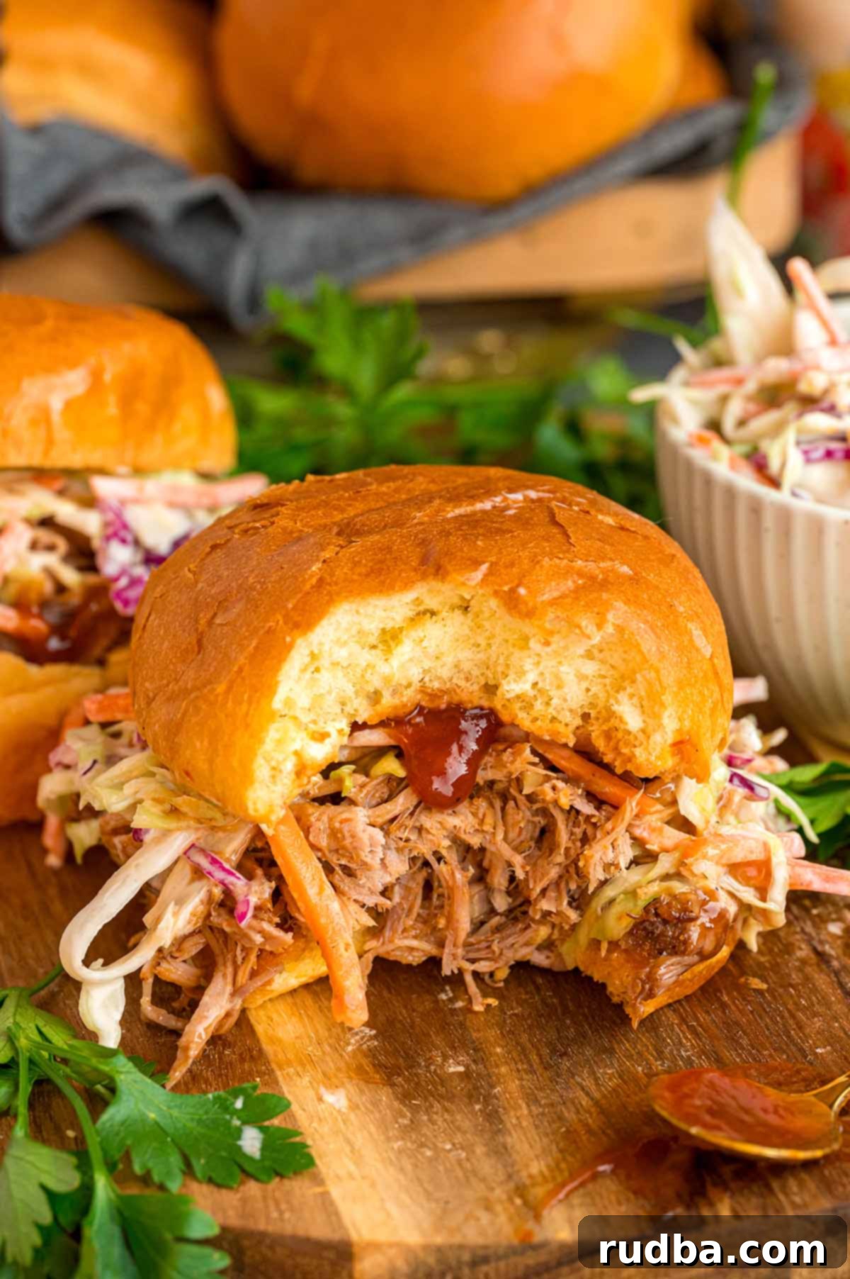 Close-up of a generous serving of pulled pork on a bun, topped with creamy coleslaw.