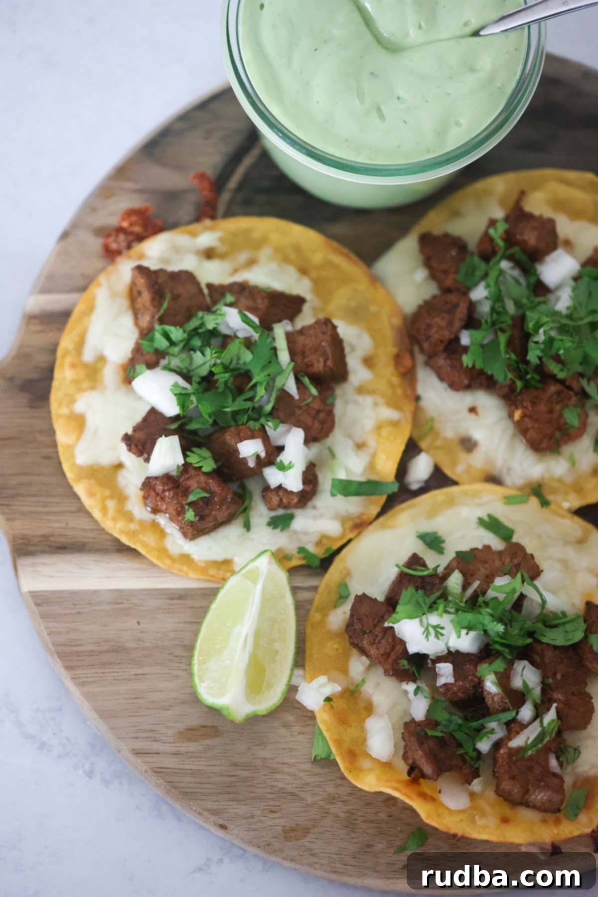 Sizzling Steak Tacos 5 Three beautifully arranged steak tacos on a rustic wooden board, garnished and ready to be enjoyed.