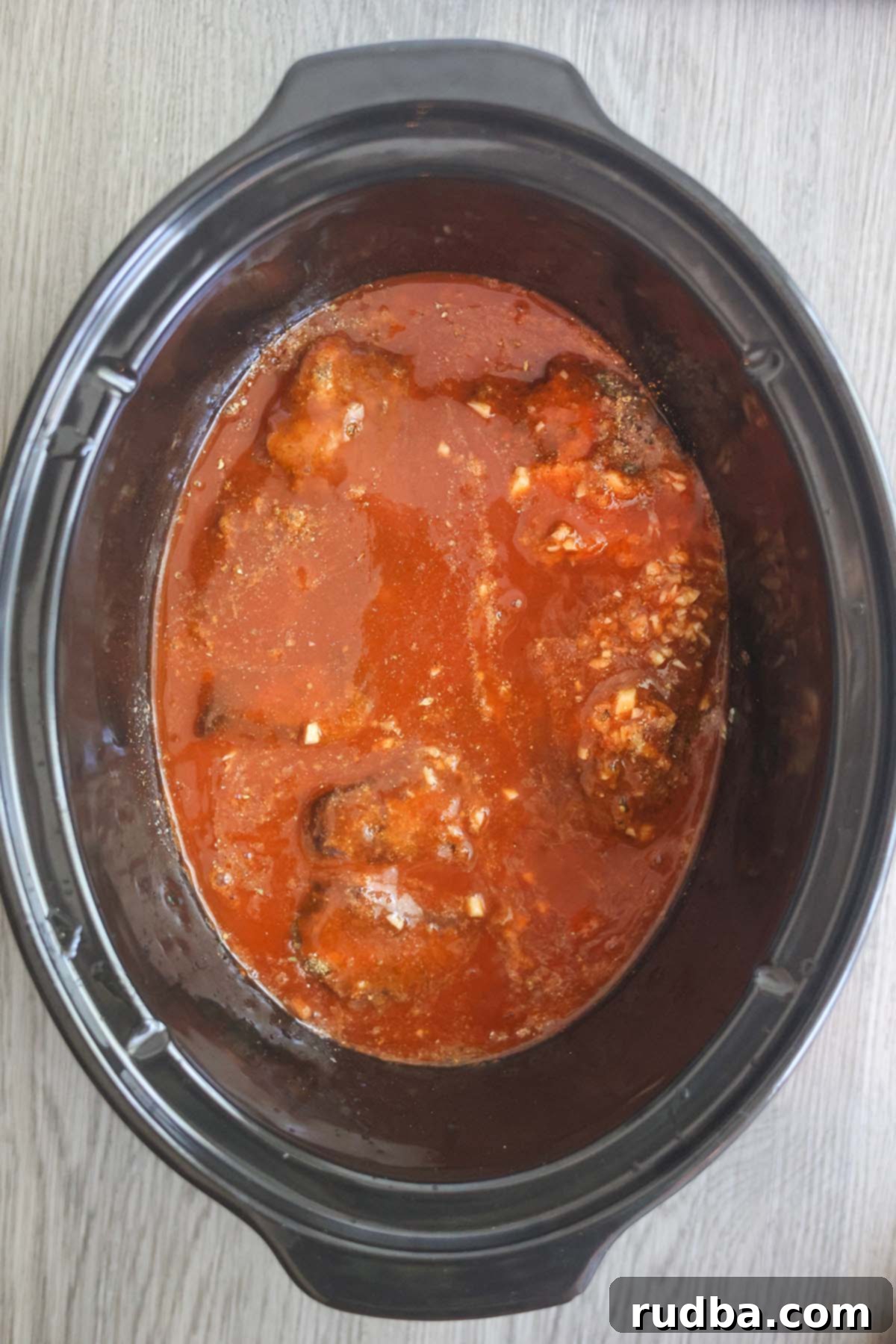 Beef, enchilada sauce, and spices simmering together in a slow cooker.