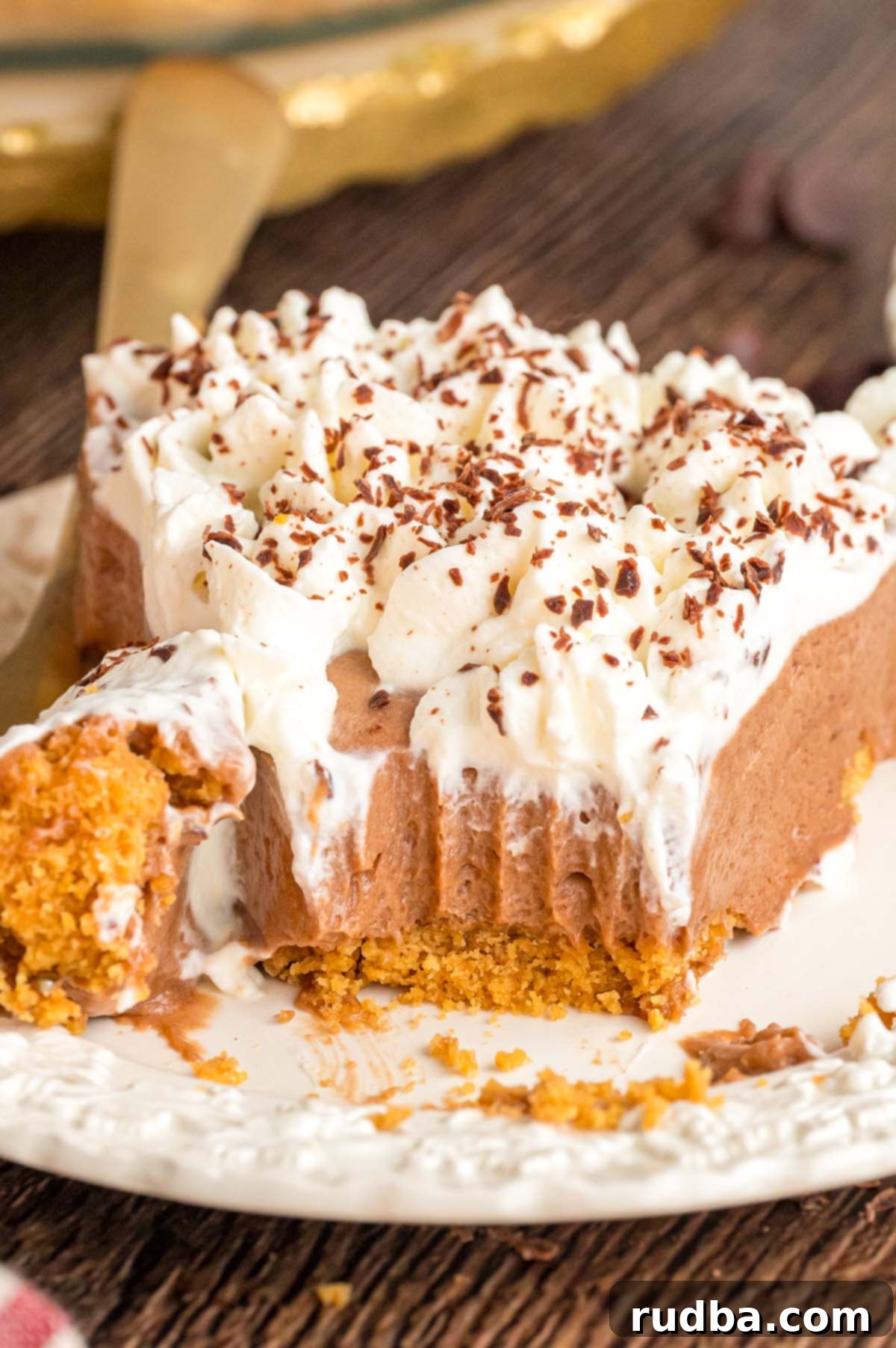 Silky Chocolate Dream Pie 2 A perfectly sliced piece of French silk pie on a white plate, showcasing its rich chocolate filling and homemade whipped cream topping.