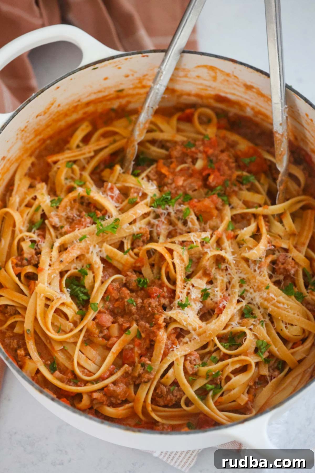 Indulgent Fettuccine Bolognese 5 Pasta in a large pot with tongs.