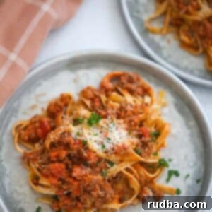 Indulgent Fettuccine Bolognese 6 two plates of fettuccine bolognese with a towel on the side.
