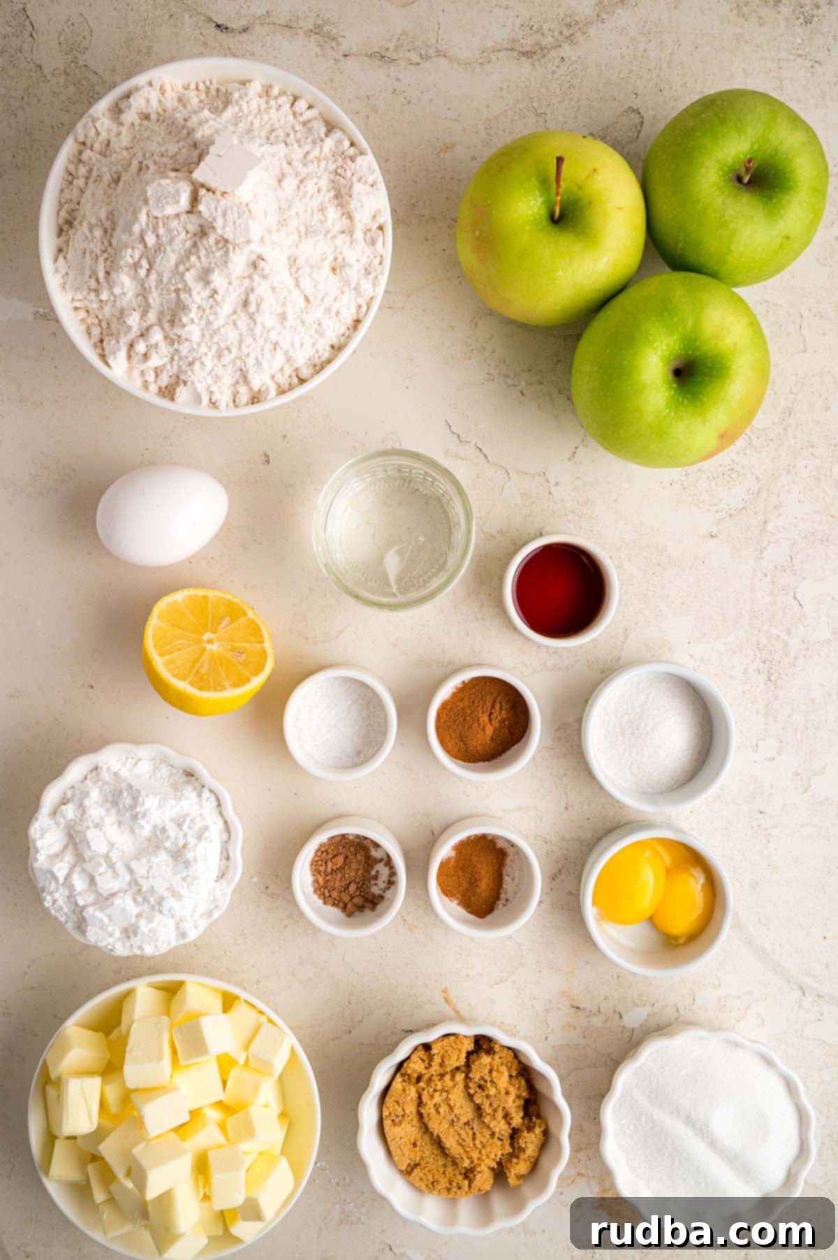 Warm Spiced Apple Pie 3 Fresh ingredients laid out on a light-colored surface, including green apples, butter, flour, and spices, ready for baking homemade apple pie.