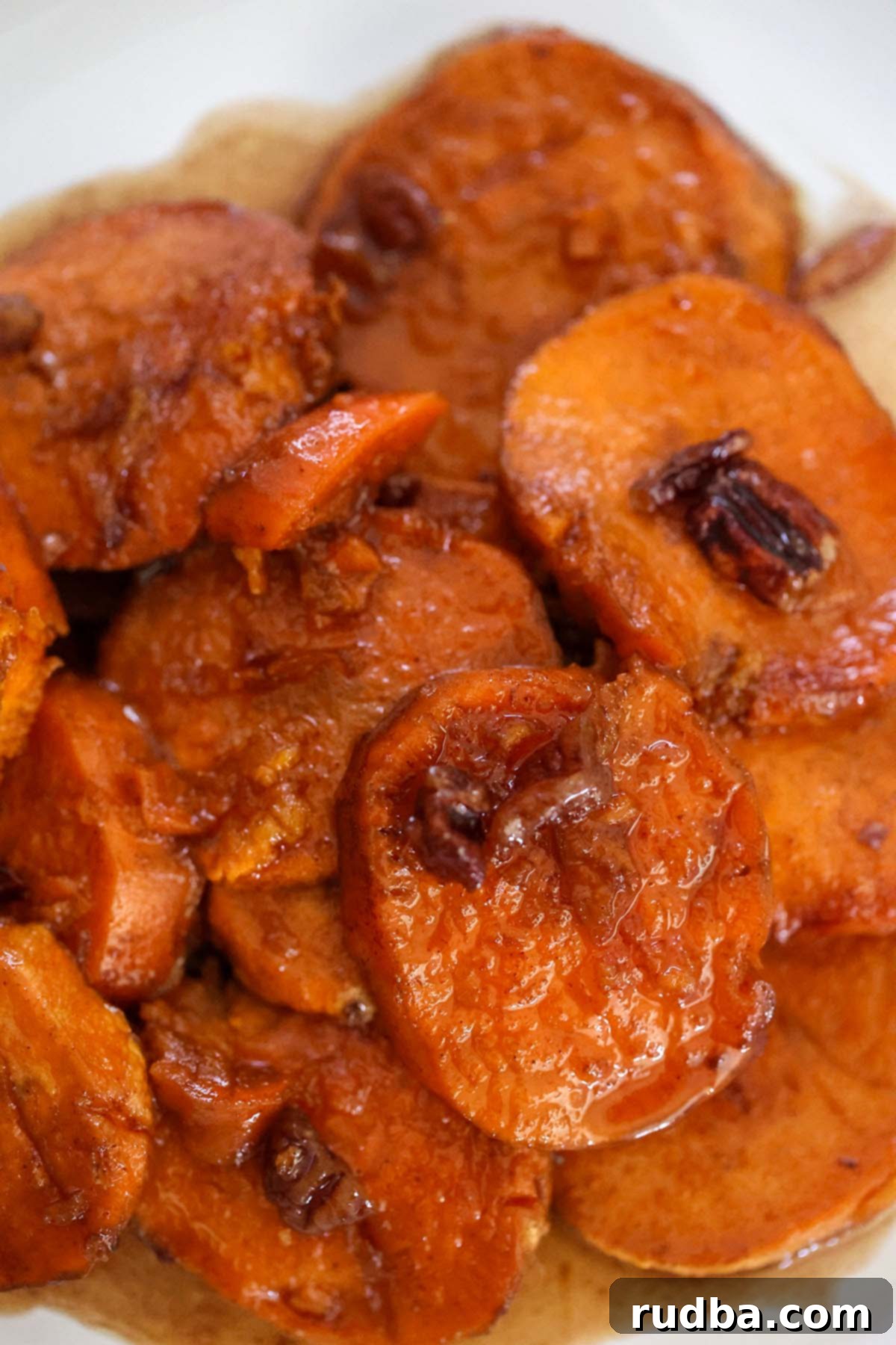 Bourbon-Kissed Sweet Potatoes 2 Bourbon candied yams with pecans on top, glistening with glaze, served in a casserole dish.