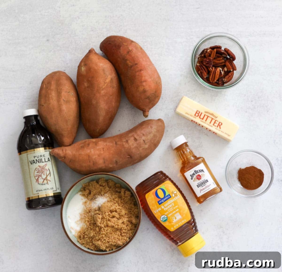 Bourbon-Kissed Sweet Potatoes 3 Ingredients for bourbon candied yams laid out, including yams, sugars, butter, bourbon, and pecans.