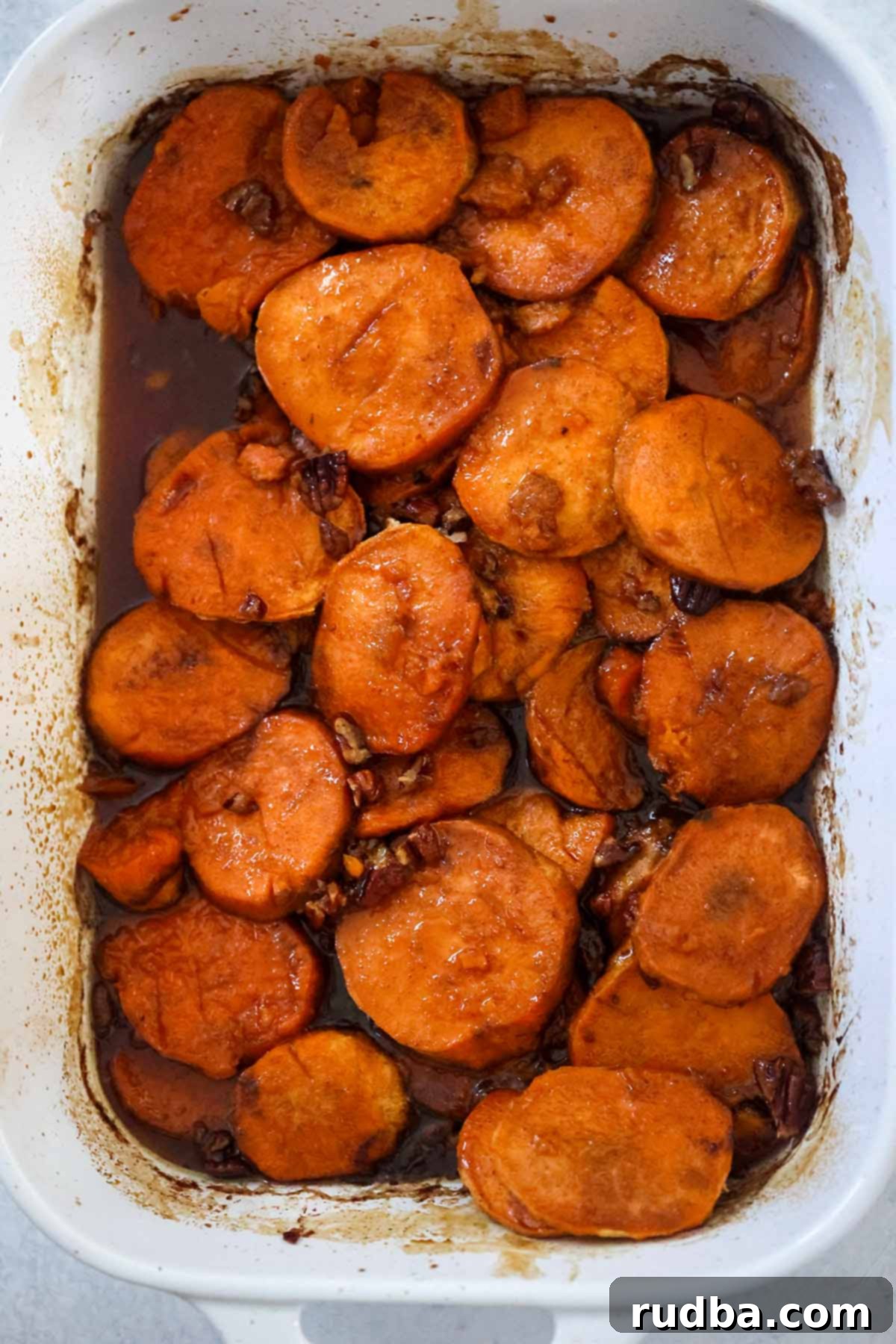 Bourbon-Kissed Sweet Potatoes 5 Baked bourbon candied yams in a white 9x13 casserole dish, fresh from the oven, ready to serve.