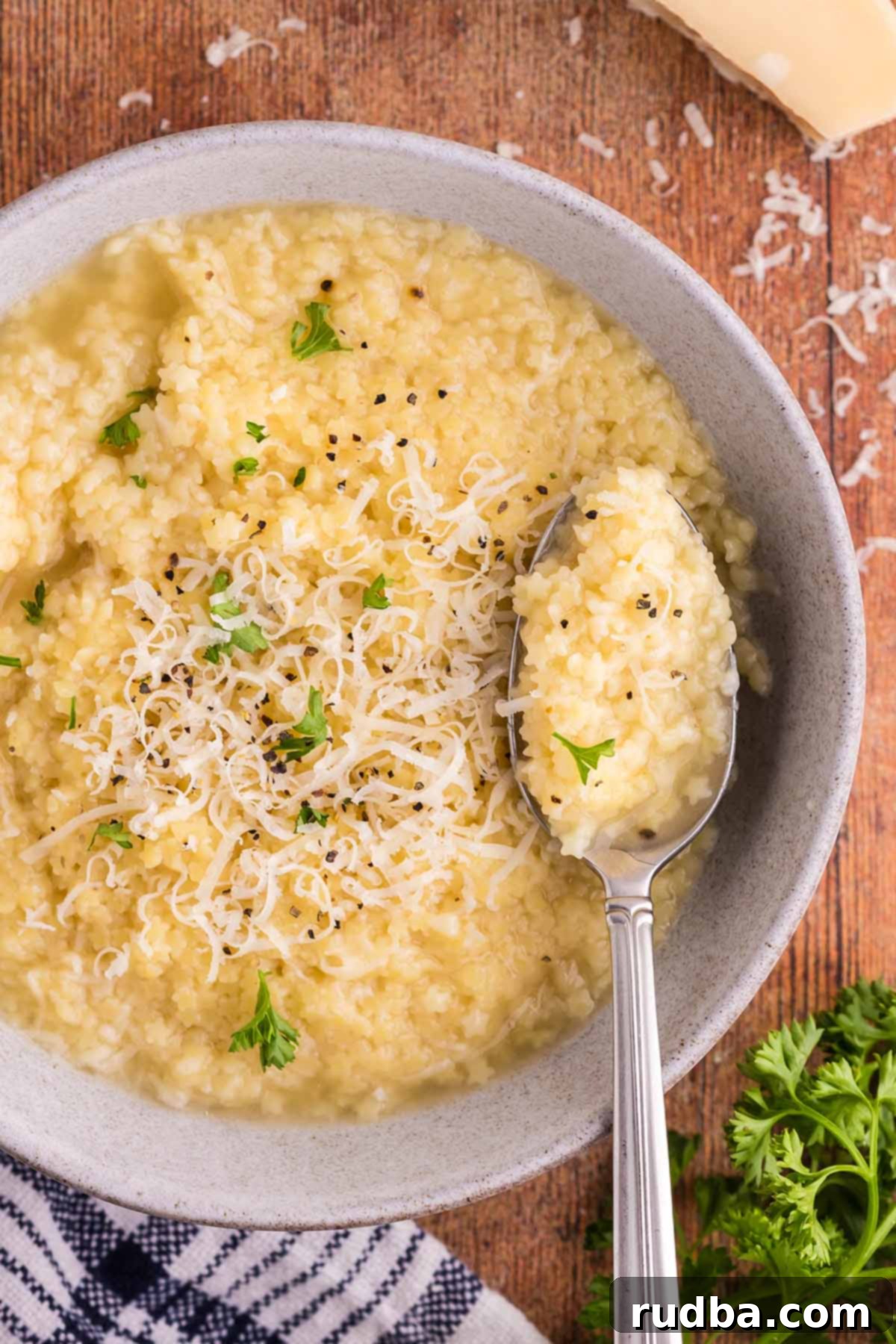 A steaming bowl of classic pastina, garnished with freshly grated Parmesan cheese and a sprinkle of vibrant parsley, ready to be enjoyed.