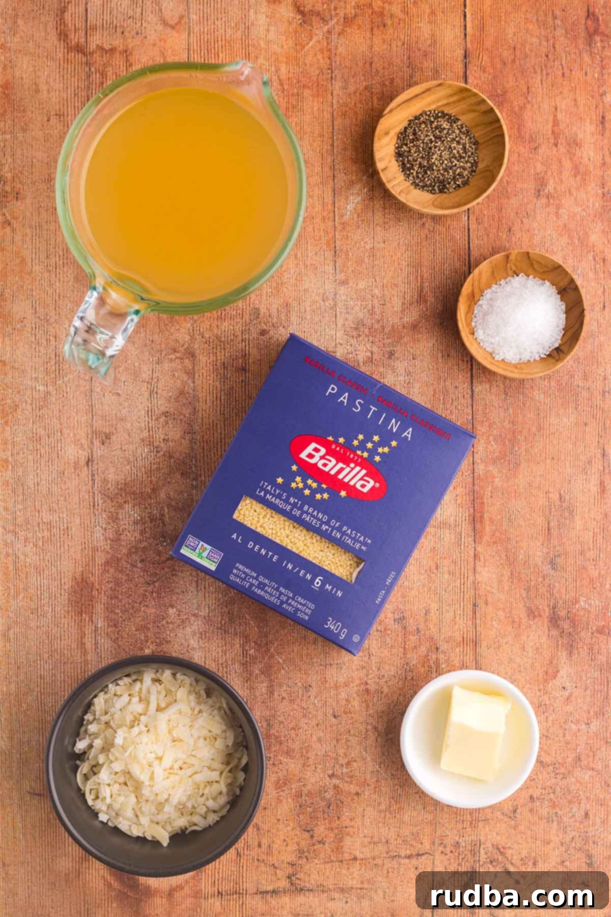 Four simple ingredients for making pastina: pastina pasta, chicken stock, butter, and a block of Parmesan cheese.