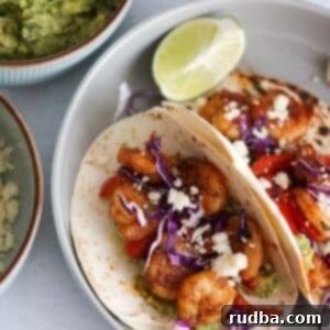 Zesty Shrimp Tacos 5 Two shrimp tacos with guacamole, limes, and cotija cheese on the side.