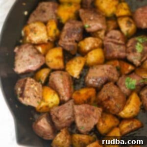 Steak bites and potato cubes in a skillet.