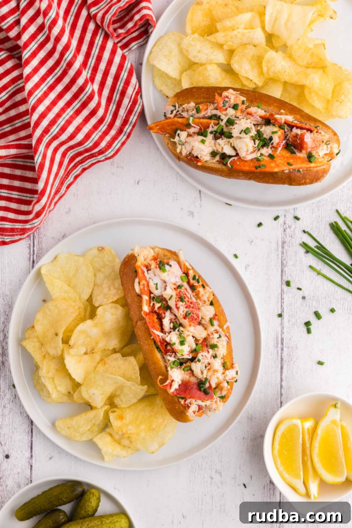 Two enticing lobster rolls served on a plate with a side of crunchy potato chips, highlighting the golden buns and rich lobster filling.