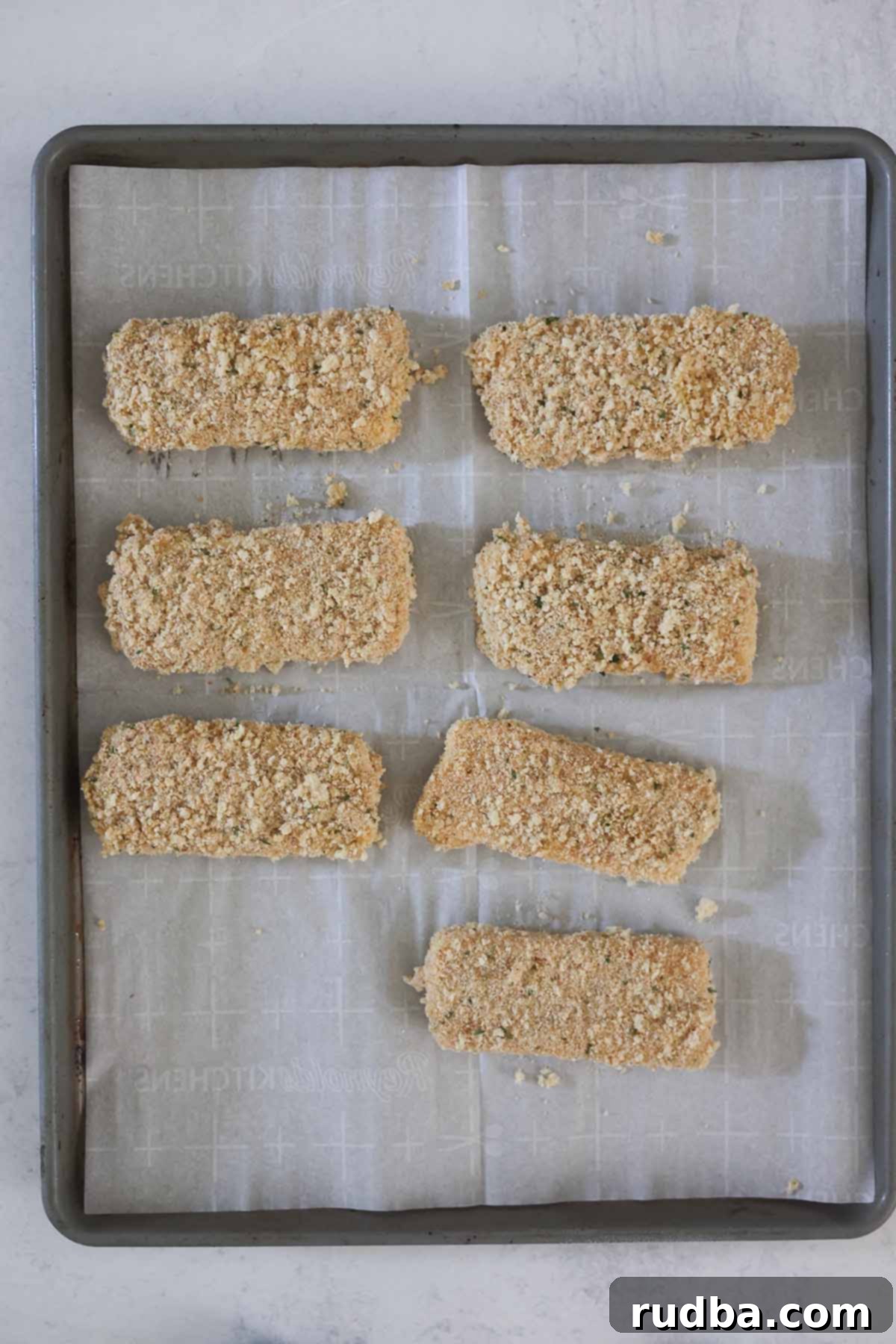 Honey Chipotle Mozzarella Poppers 3 Seven bread crumb coated mozzarella sticks arranged neatly on a baking sheet, ready for freezing.