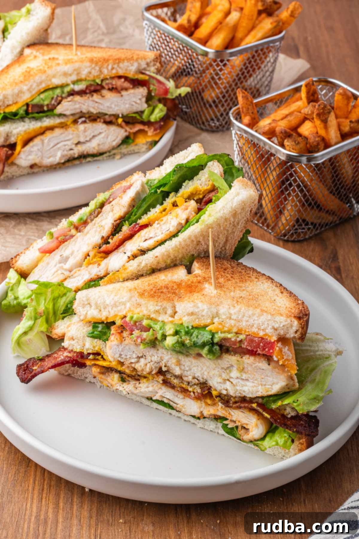 Ultimate Chicken Club 2 A chicken club sandwich with French fries on the side, showcasing its delicious layers.