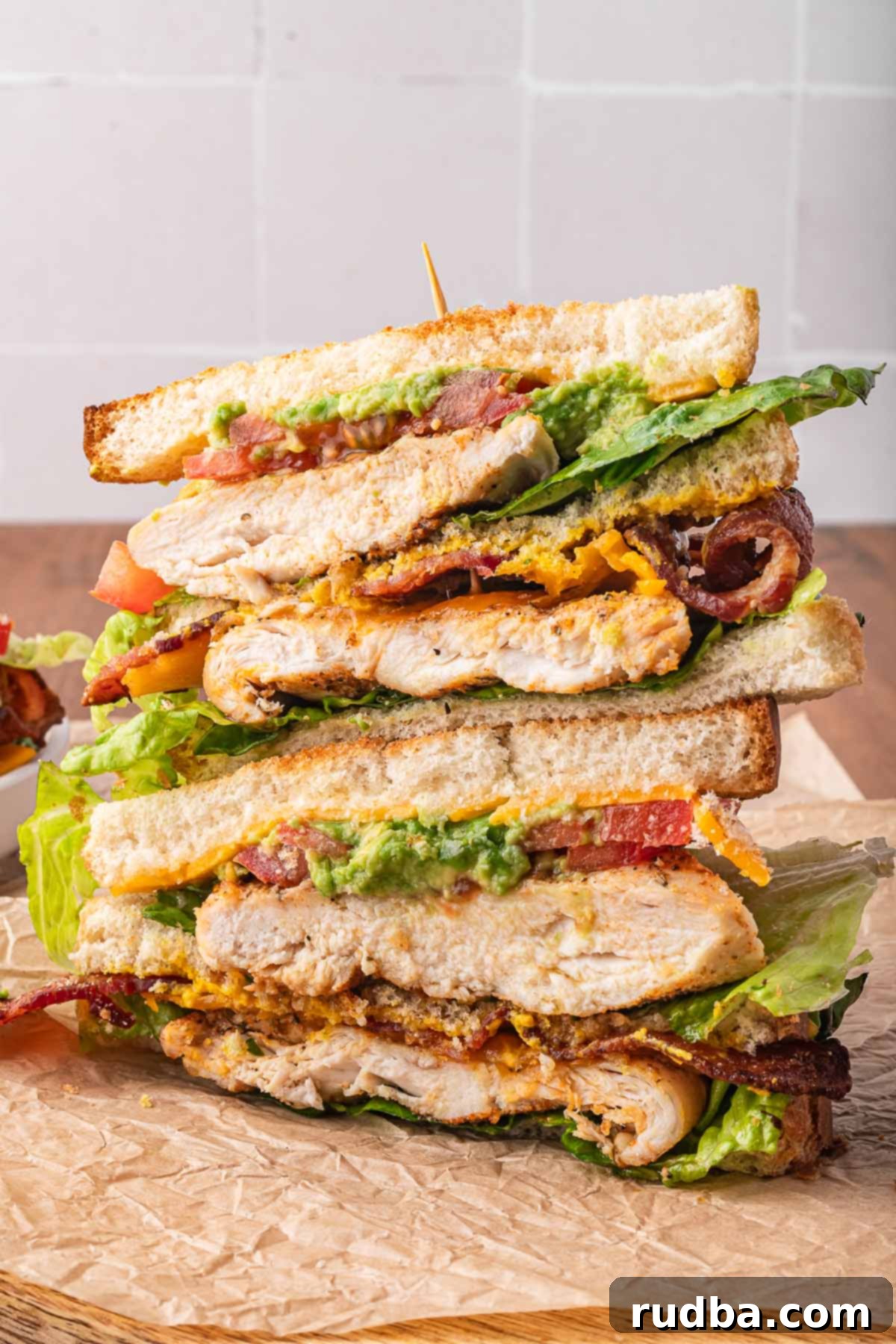 Ultimate Chicken Club 4 Stacked chicken club sandwiches on a cutting board, ready to be served.