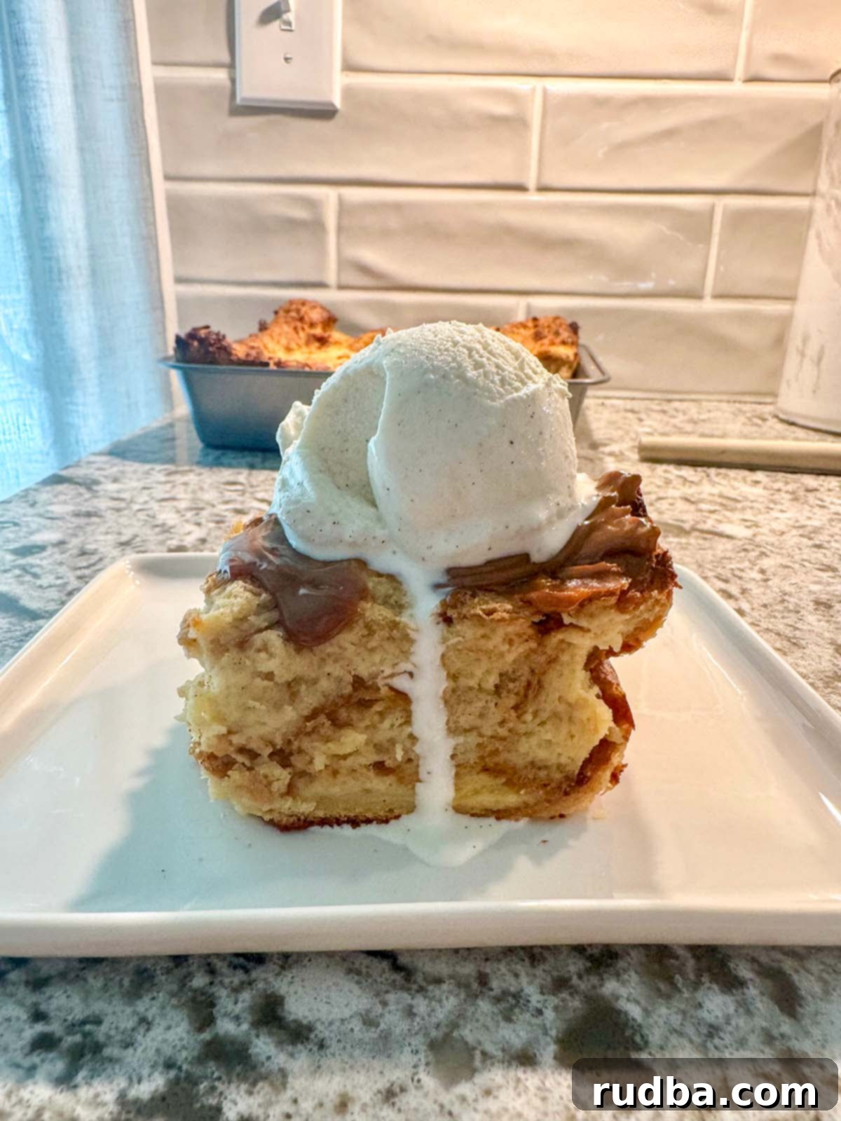 Authentic Cuban Bread Pudding 2 A perfectly sliced piece of warm Cuban bread pudding, topped with a melting scoop of vanilla ice cream, creating a delightful contrast of temperatures and textures. A drizzle of golden dulce de leche cascades down the side.