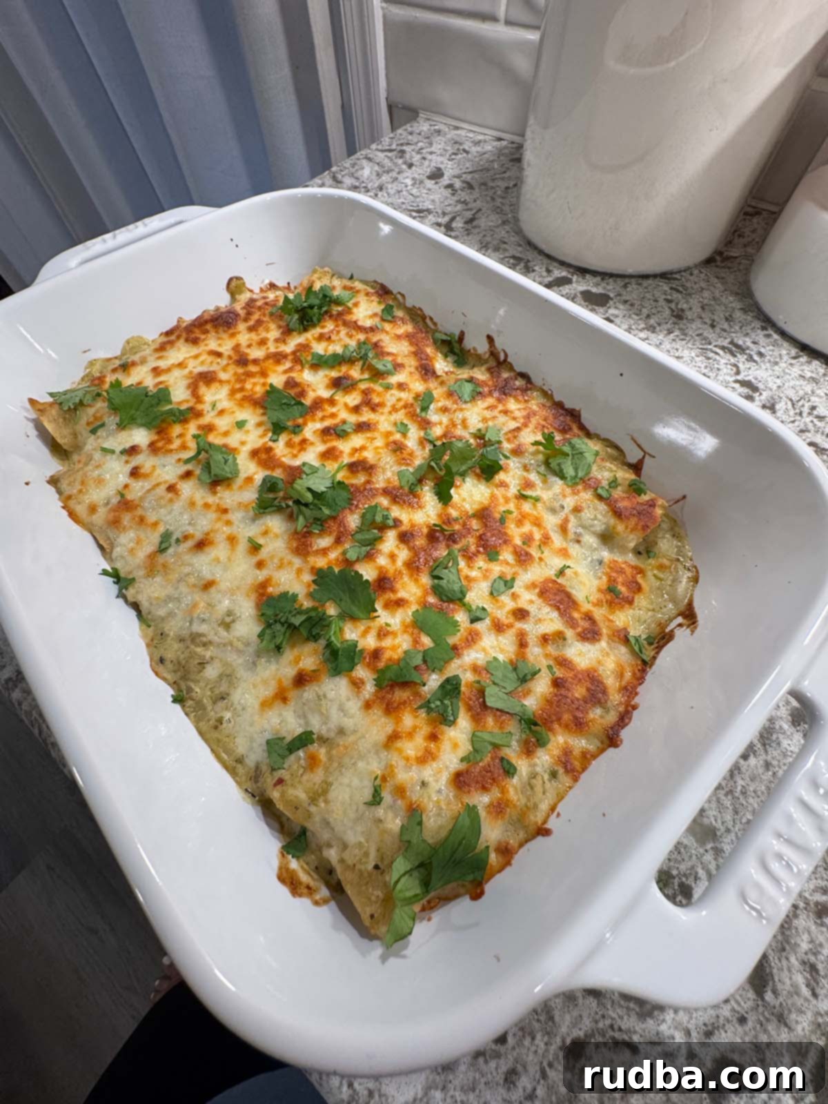 Ultimate Green Chile Chicken Enchiladas 4 Baked Green Chile Chicken Enchiladas, golden and bubbly, in a white 9x13 baking dish, straight from the oven.