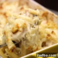 Title Localization 3 Close-up of baked chicken and shrimp pasta with melted cheese topping, fresh out of the oven.