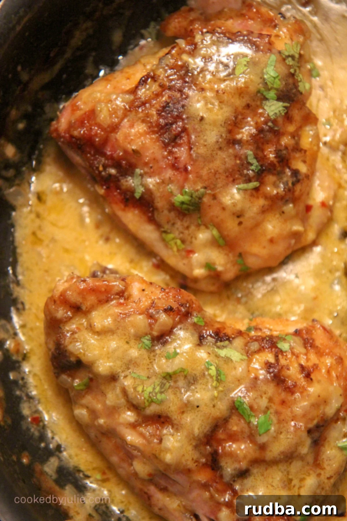 two chicken thighs with cream in a black skillet