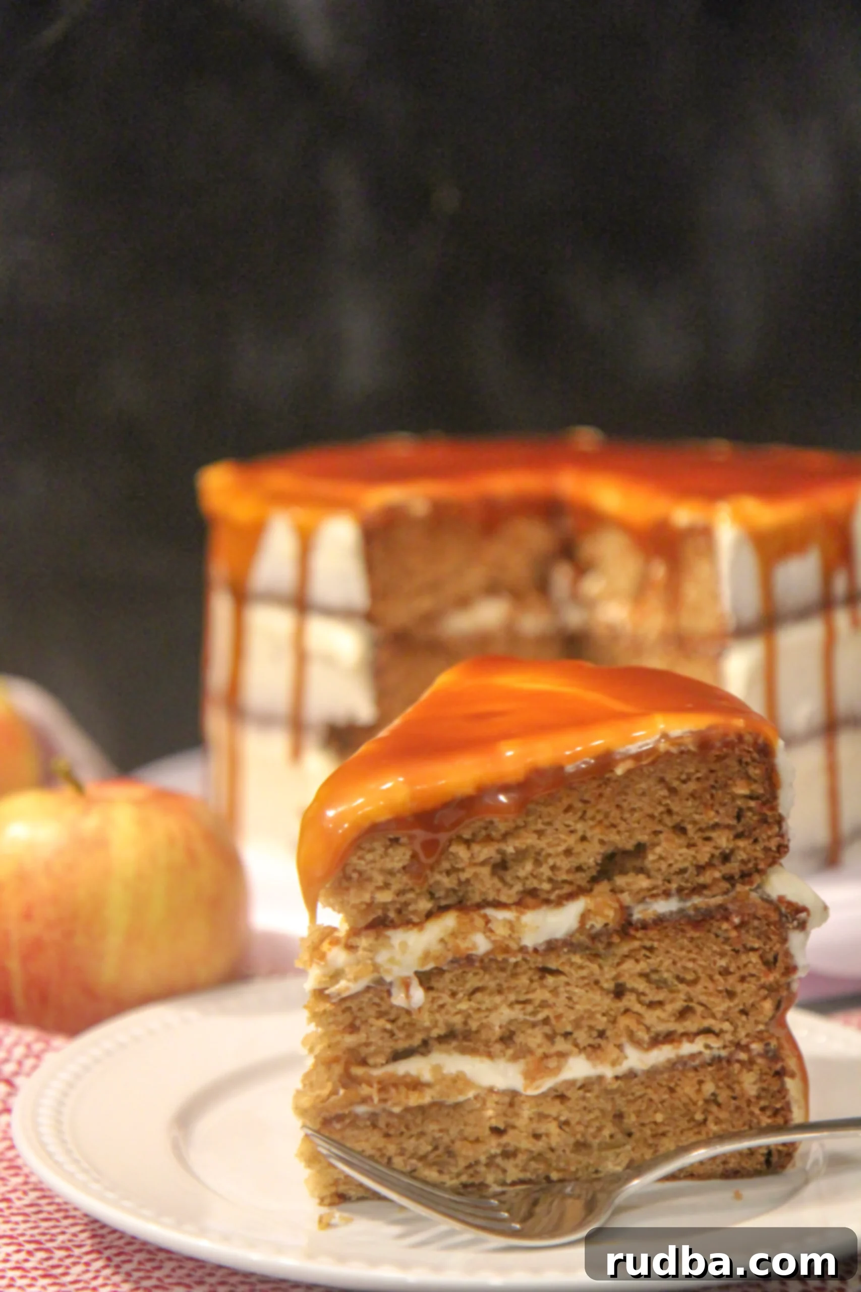 A delectable slice of salted caramel apple cake, showcasing its moist layers, rich cream cheese frosting, and luscious caramel drizzle.
