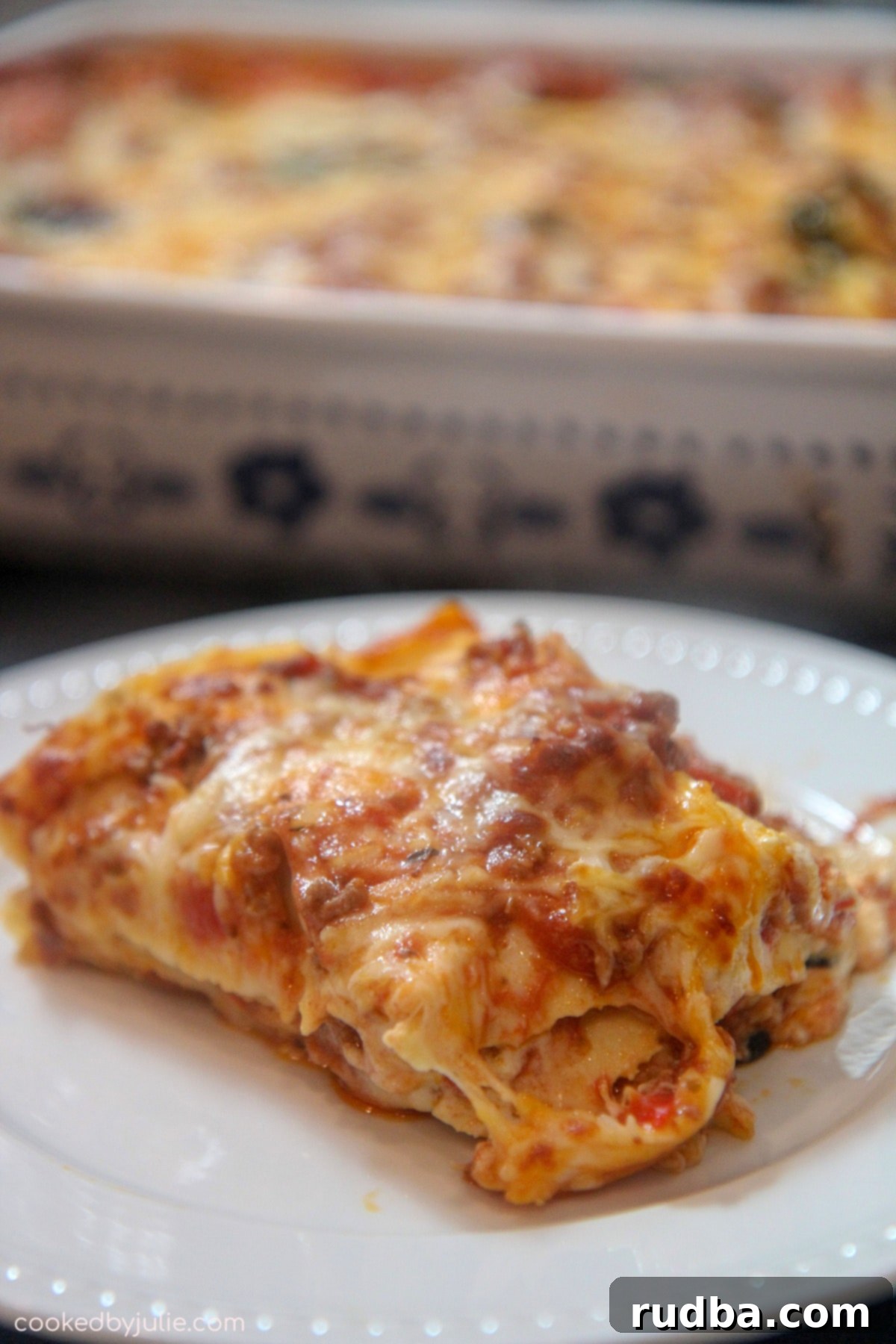 A close-up of a serving of Cajun lasagna on a white plate, garnished with fresh basil, showing the delicious layers.