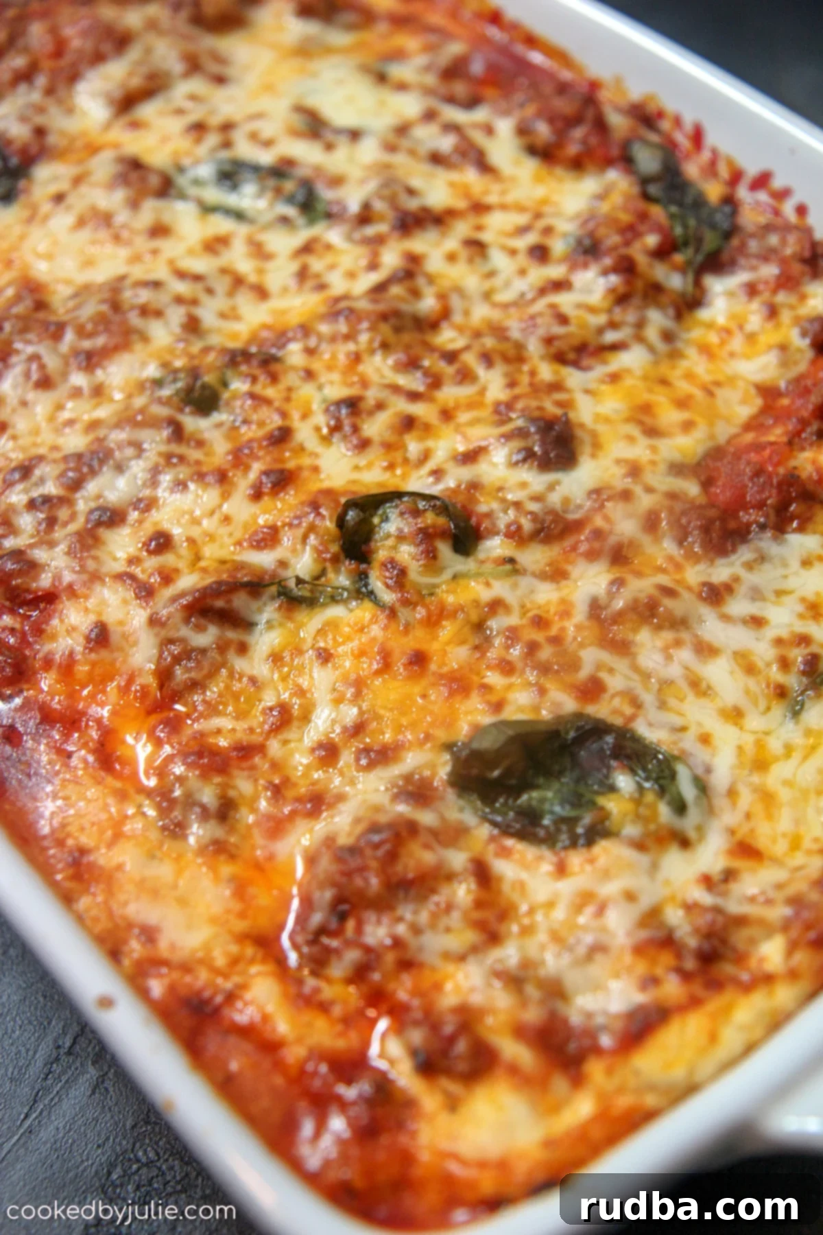 Cajun lasagna baking in a glass dish, still bubbling with melted cheese and sauce around the edges.