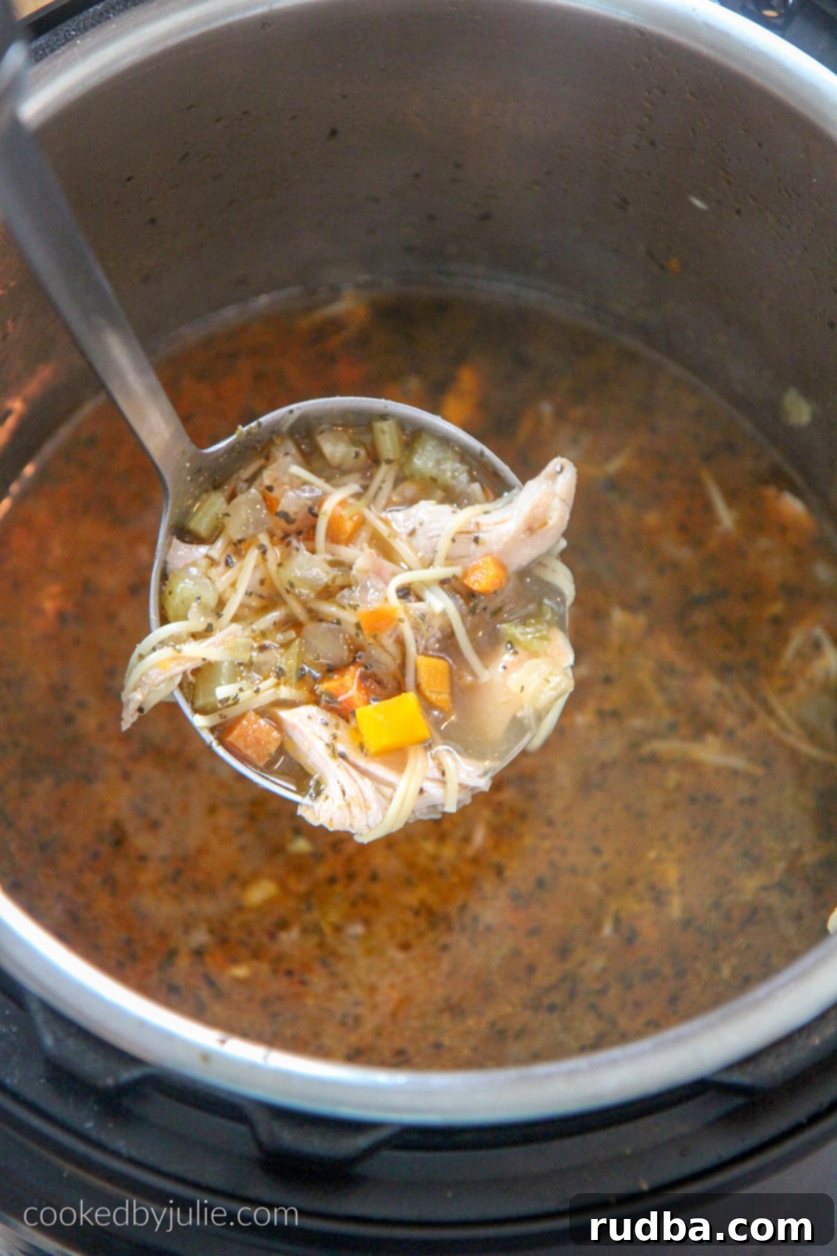 A large ladle scooping Instant Pot Chicken Noodle Soup directly from the Instant Pot, showing the rich broth and noodles.