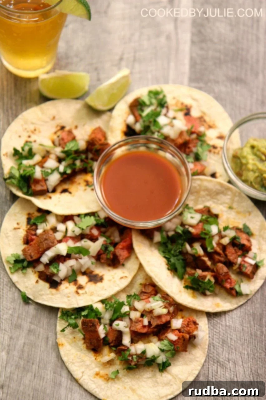 Homemade carne asada tacos served with chopped cilantro, onions, and lime on a rustic wooden board, ready to be enjoyed.