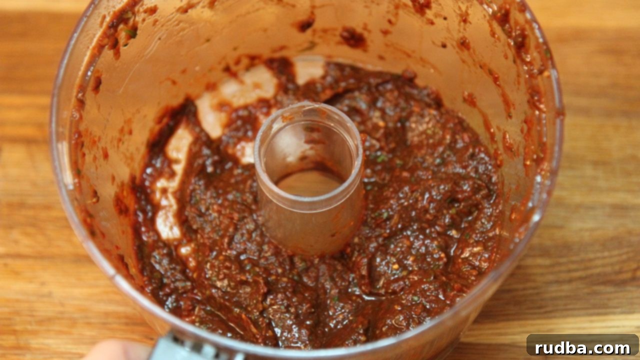 Blending rehydrated chilis with garlic, citrus, and other spices to create a rich, flavorful chili paste marinade for carne asada tacos.