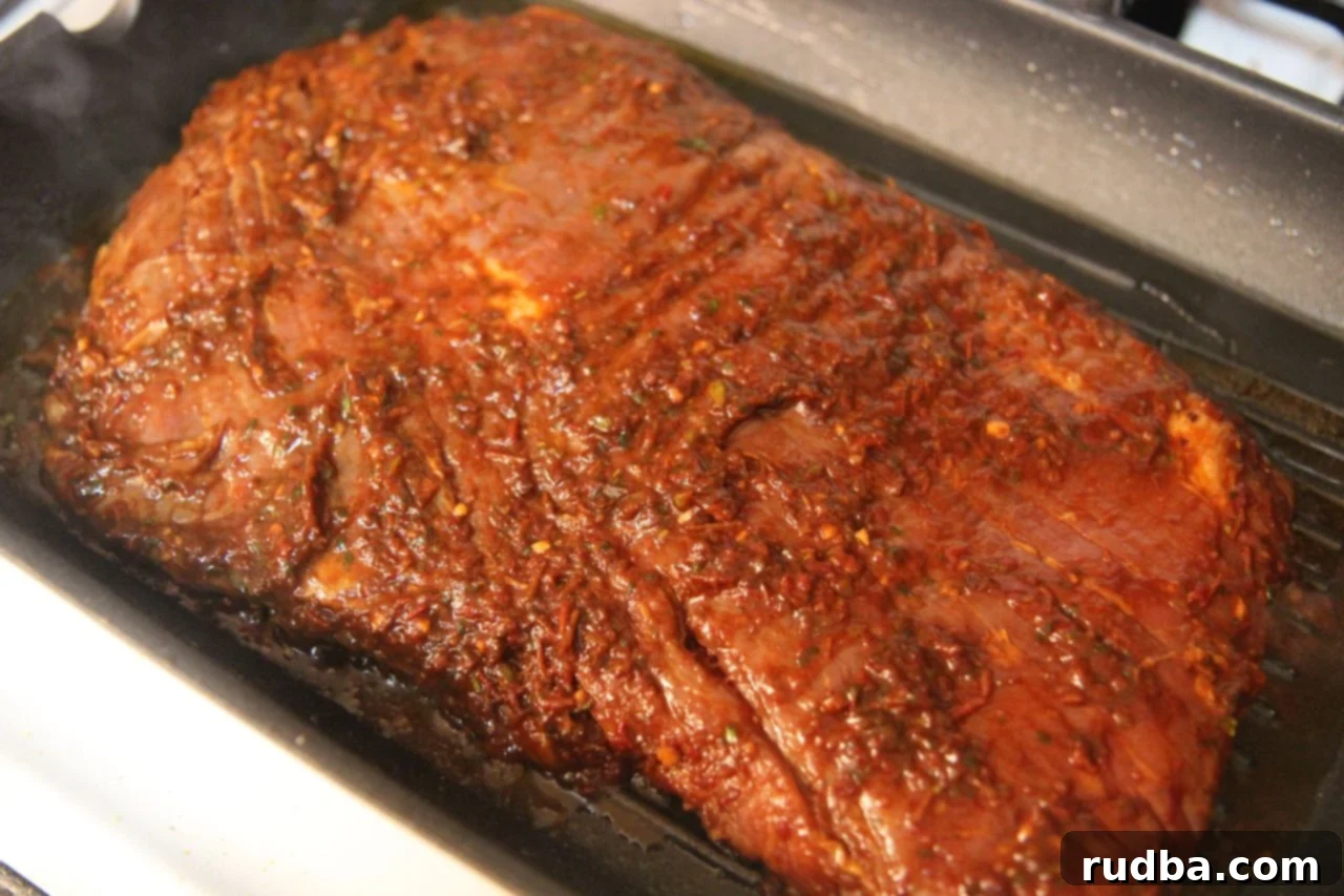 Marinating a flank steak in a vibrant red pepper sauce, ensuring it absorbs maximum flavor for juicy and tender carne asada tacos.