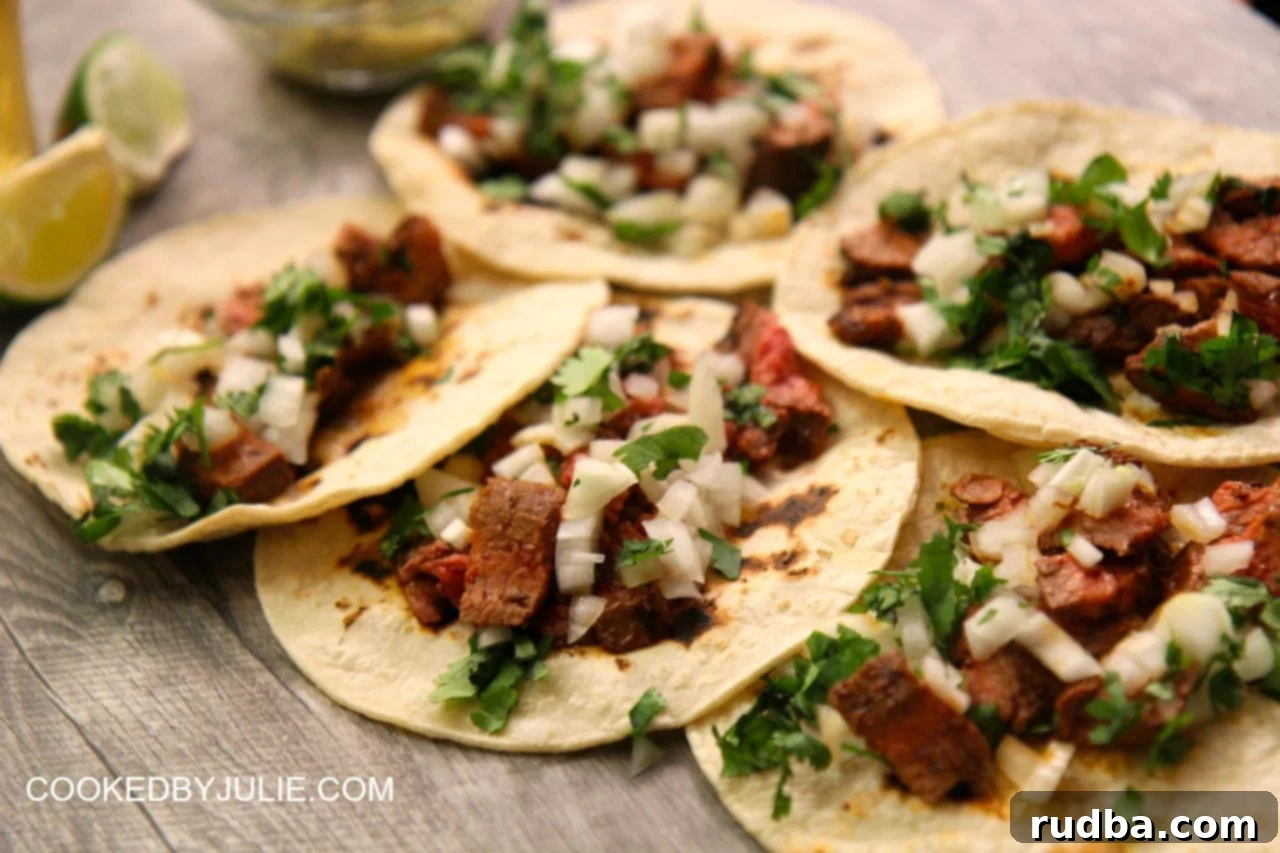 Delicious homemade carne asada tacos artfully arranged on warm corn tortillas, garnished with finely chopped onions and fresh cilantro, and a wedge of lime.