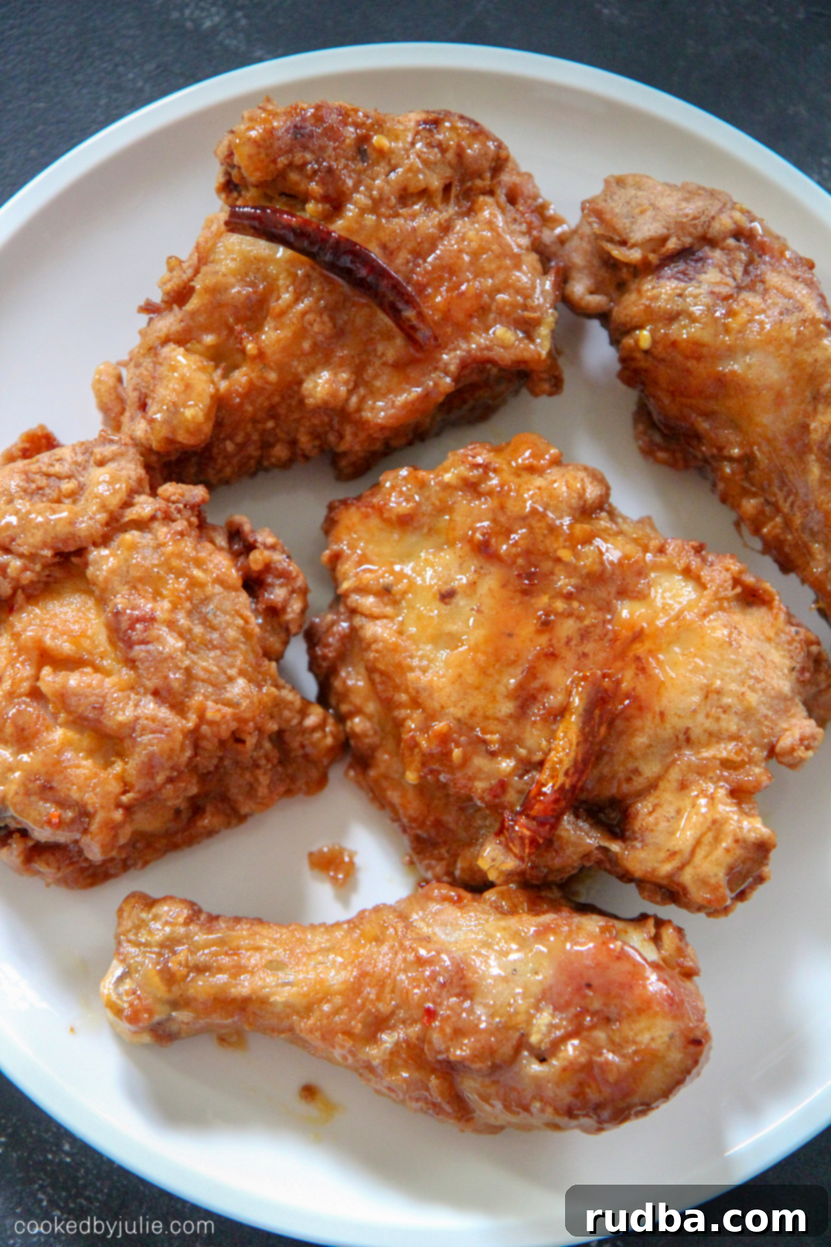Three pieces of crispy and juicy honey butter chicken, perfectly golden brown and coated in a shiny sauce, resting on a serving plate.