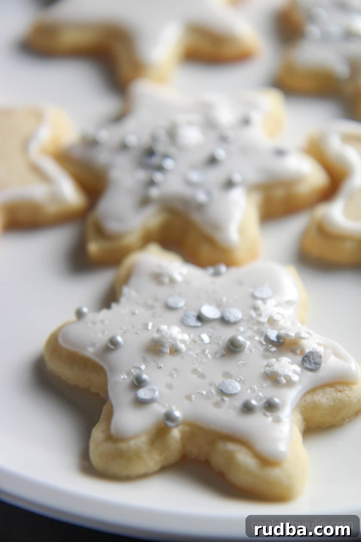 Six perfectly cut out sugar cookies on a pristine white plate, showcasing their inviting texture.