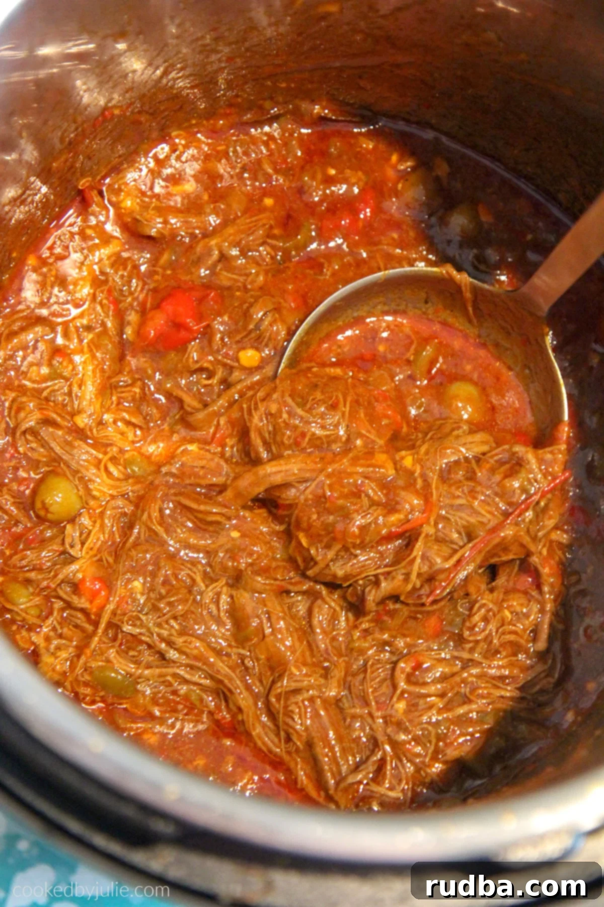 Shredded flank steak simmering in a rich, spiced tomato broth for Ropa Vieja