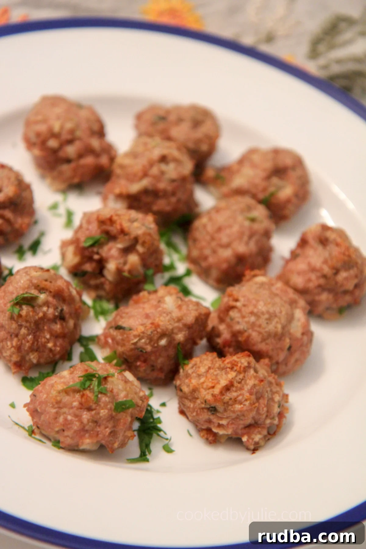 Baked turkey meatballs on a white and blue plate, garnished with fresh parsley.