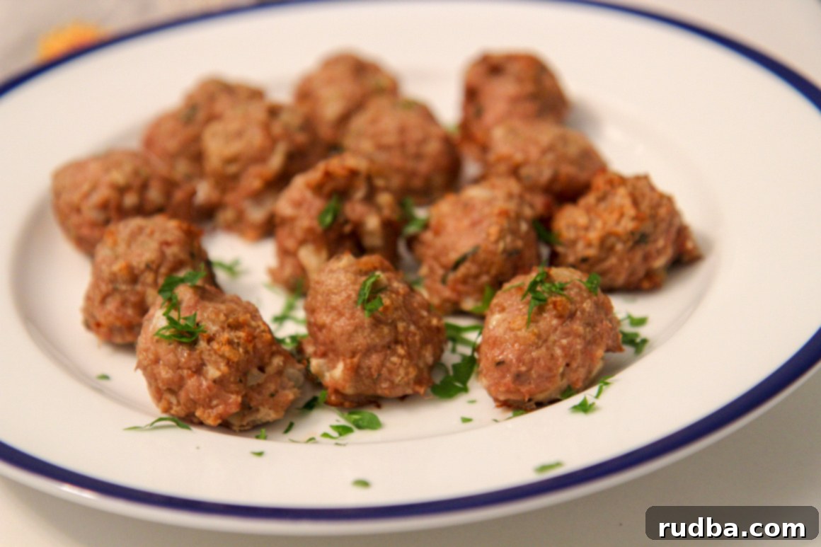 A white and blue plate filled with baked turkey meatballs, garnished with fresh green parsley.
