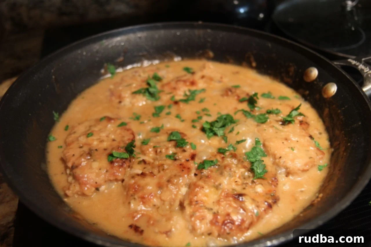 smothered pork chops, parsley, in a black skillet. 