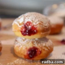 Jam Doughnuts 4 jelly donuts with powdered sugar stacked on top of a wooden board