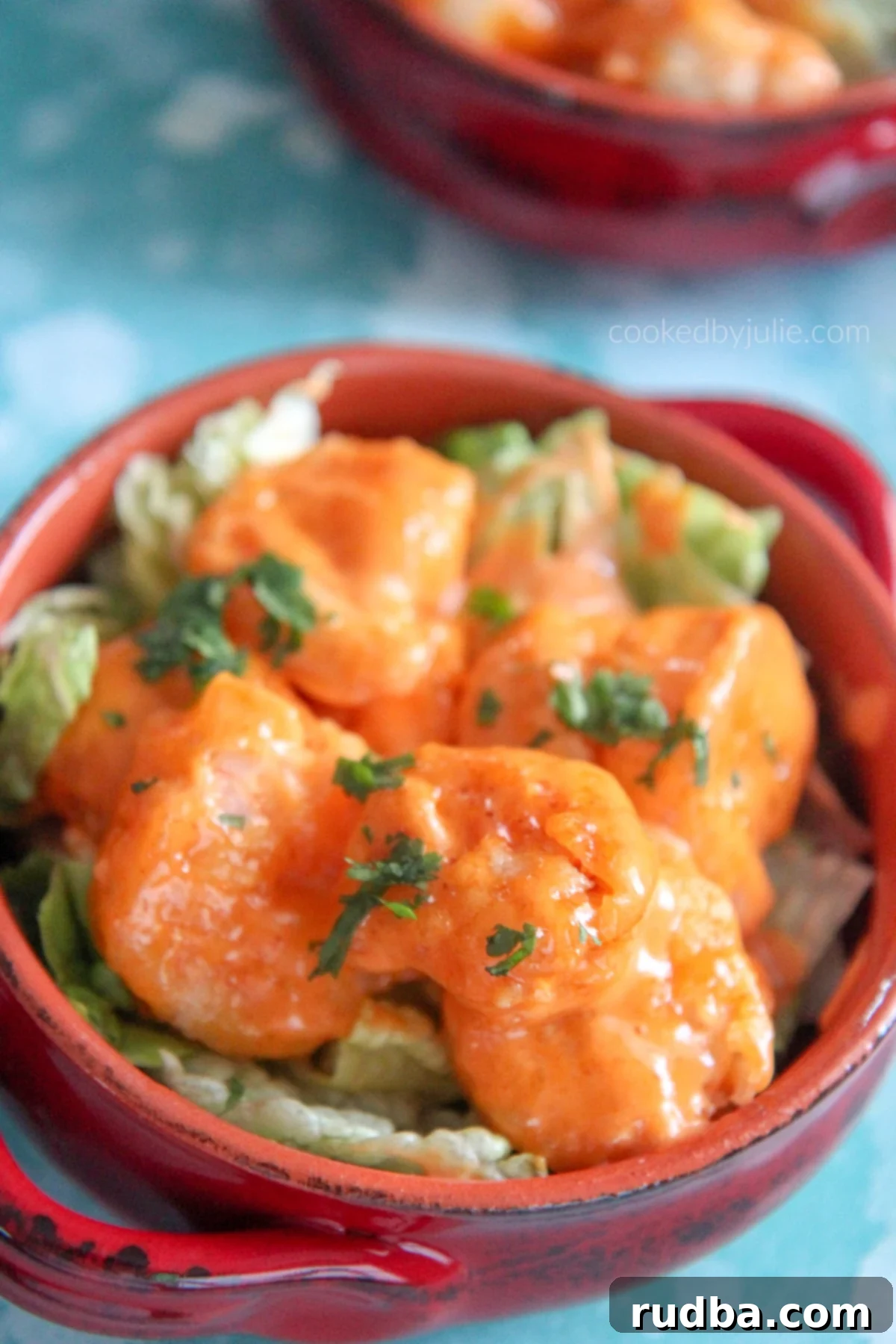 Crispy Bang Bang Shrimp served over fresh lettuce in a vibrant red bowl, ready to be enjoyed.