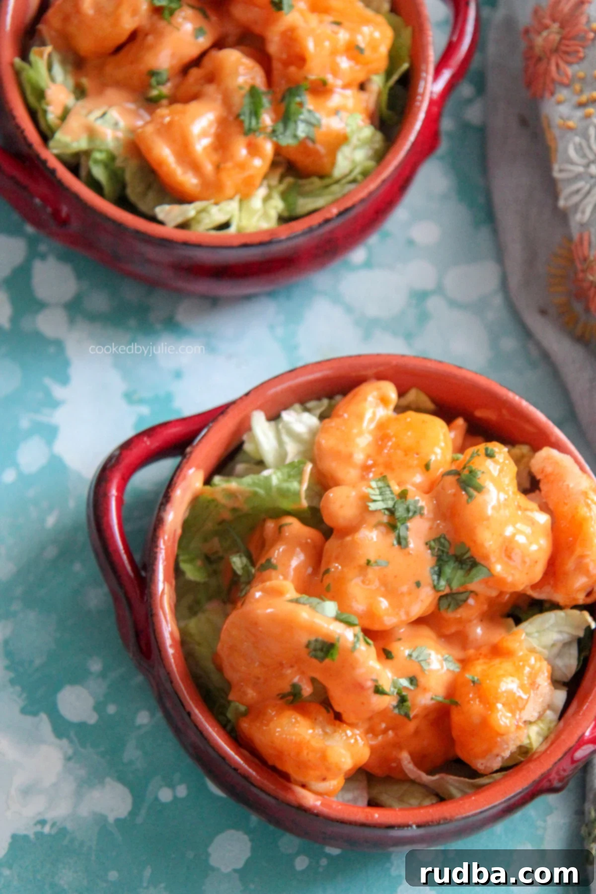 Close-up of fried shrimp coated in a luscious mayo-based dressing, garnished with fresh parsley, ready to be served.