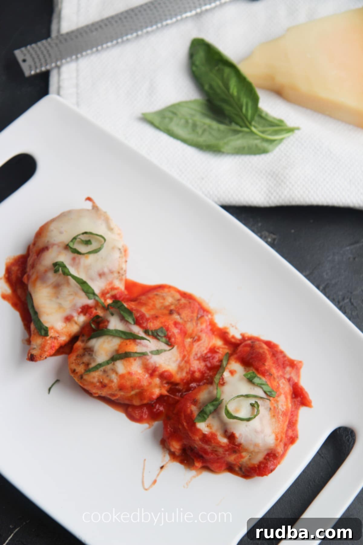 Close-up of a serving of grilled chicken parmesan, showing melted cheese, fresh basil, and rich tomato sauce.