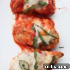 Three servings of grilled chicken parmesan with sauce, cheese, and basil served on a white plate